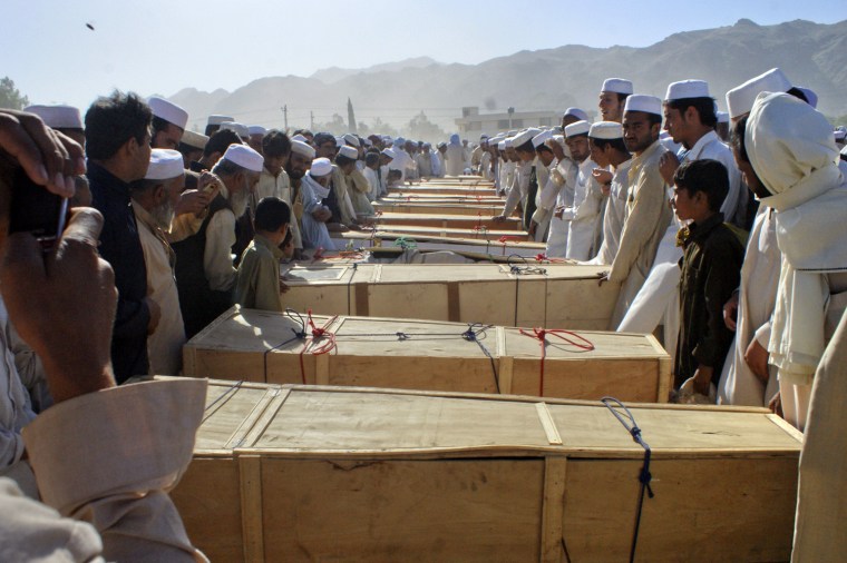 Image: Residents stand over the caskets of those killed by a secondary blast at the site of a NATO tanker which was attacked in Pakistan's northwest Khyber Agency