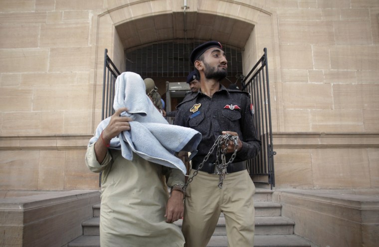 Image: Policemen escort men, who police said were paramilitary officials charged in the death of an unarmed man, after they were brought before a judge at a court in Karachi