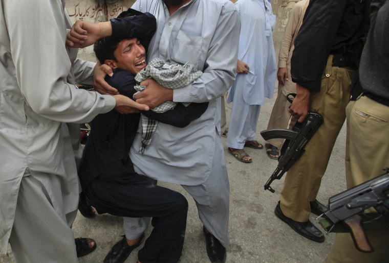 Image: Family members hold onto a man, crying as the body of his dead brother, a policeman, is brought to the Lady Ready Hospital in Peshawar