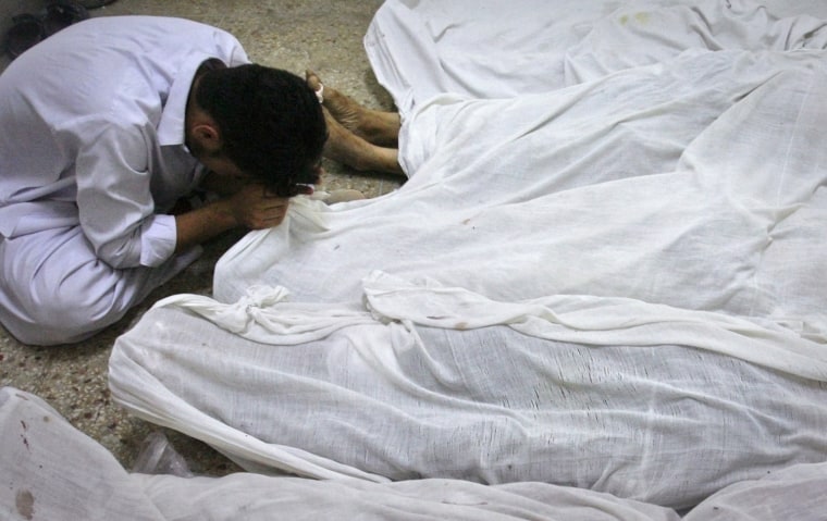 Image: A man holds the feet of his brother, who was killed by unidentified gunmen in a shootout, at a hospital in Quetta