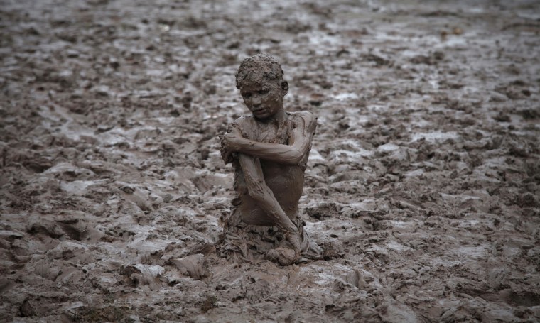 Image: A boy plays in the mud near the Ravi river after a downpour on the outskirts of Lahore
