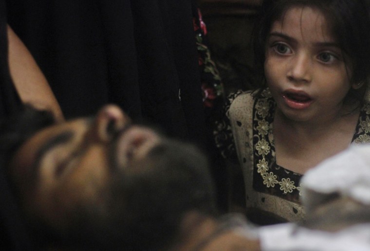 Image: A girl whose uncle was injured in a shootout by unidentified gunmen, looks at him as he is brought to a hospital for treatment in Karachi