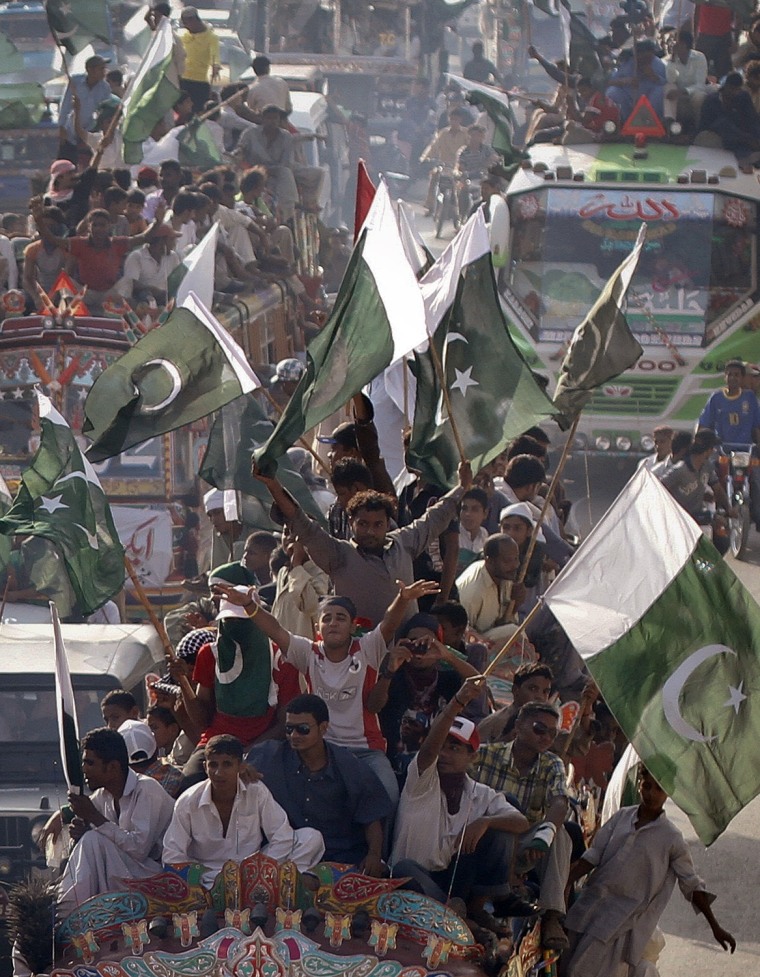Image: Supporters of Pakistan People's Party wave their country's national flags from atop bus while taking part in anti-American rally near U.S. consulate in Karachi