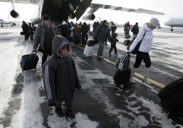 Image: Russian citizens, who were evacuated from Libya, leave a plane owned by the Russian Emergency Situations Ministry as they walk along a landing runway at Domodedovo airport outside Moscow