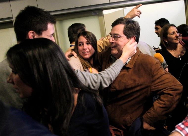 Image: A Spanish man is reunited with relatives after arriving from Tripoli to Madrid's Barajas airport