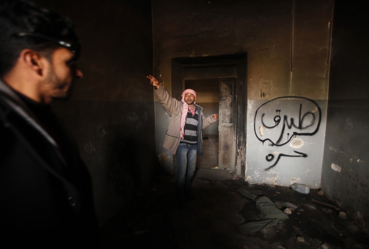 Image: Man gestures inside a burnt state security building in Tobruk east of Libya
