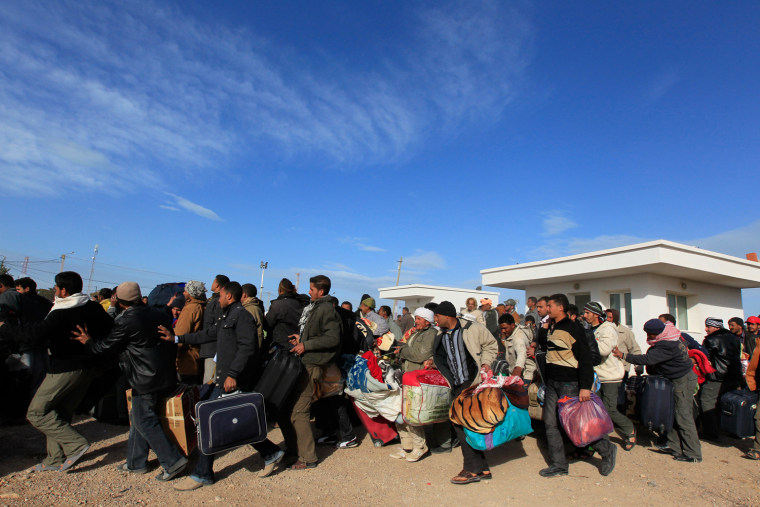 Image: Egyptians rush to take buses at the Libyan and Tunisian border crossing of Ras Jdir