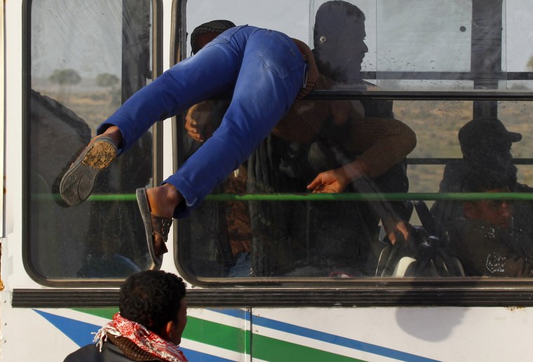 Image: An Egyptian refugee enters a bus from the window at a refugee camp after crossing into Tunisia to flee the violence in Libya near the border crossing of Ras Jdir
