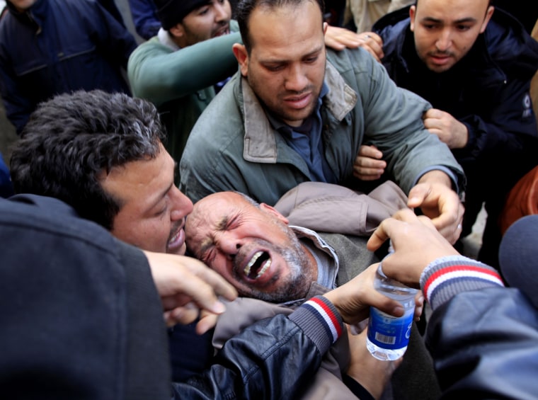 Image: A Libyan mourner is held as he collapses during the funeral of Elgadi in the Tajoora neighborhood of Tripoli