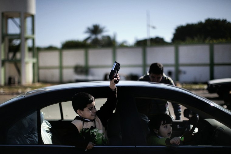 Image: A young Libyan boy holds a toy gun while