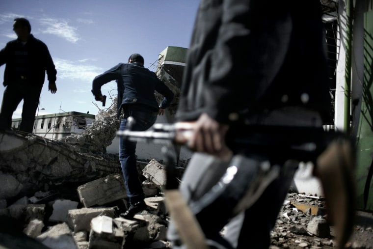 Image: Armed Libya civilians walk over the debr