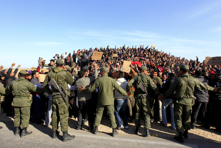 Image: Tunisian army soldiers try to calm down Egyptians during a protest by a refugee camp near the Libyan and Tunisian border crossing of Ras Jdir