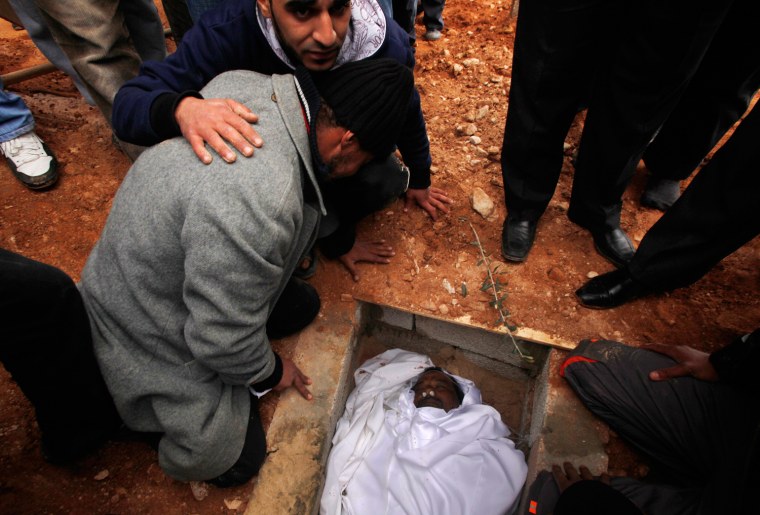 Image: Mourners react next to the grave of Itrenah, who died from injuries sustained during recent clashes, at his funeral in a cemetery in Benghazi