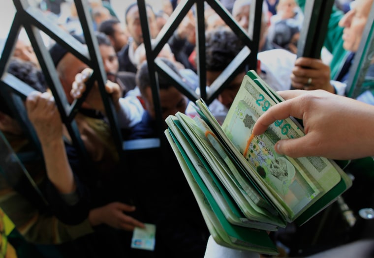 Image: People wait to collect their cash handouts at a bank in Tripoli