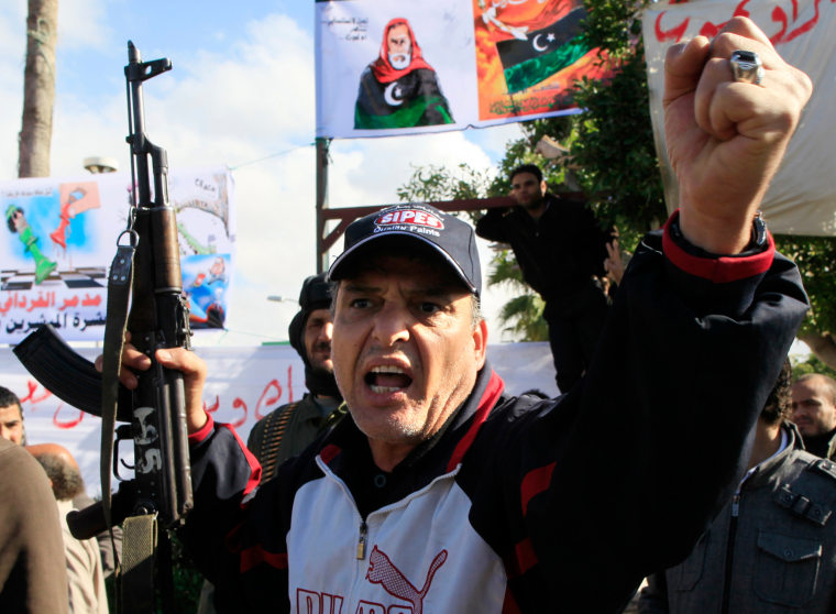 Image: A man opposed to leader Muammar Gaddafi holds a Kalashnikov rifle in the centre of the city of Zawiyah