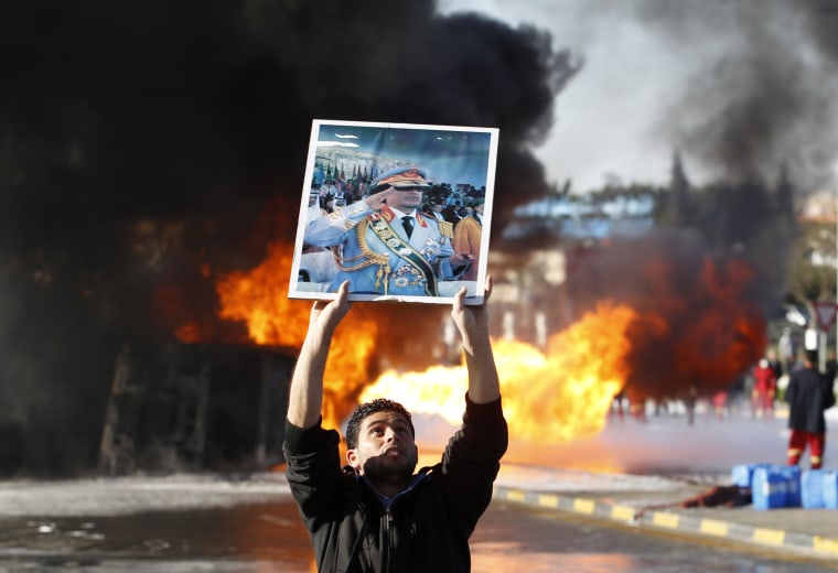 Image: Man holds up a poster of Libya's leader Muammar Gaddafi in Tripoli