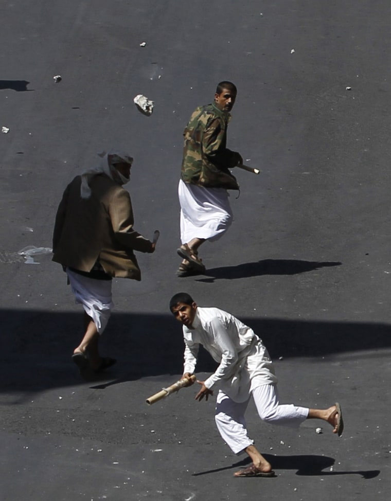 Image: A government backer hurls a rock during clashes with anti-government protesters in Sanaa