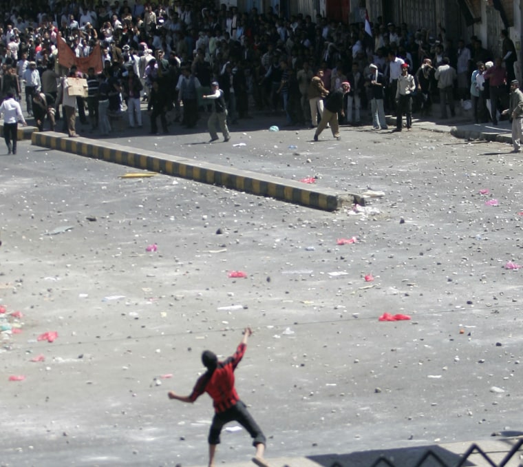 Image: Government backer hurls rocks at anti-government protesters during clashes in Sanaa