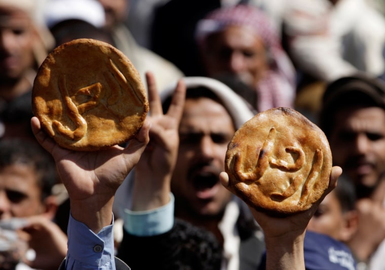 Image: Protesters hold up pieces of bread with the word Leave! on them during an anti-government rally outside Sanaa University