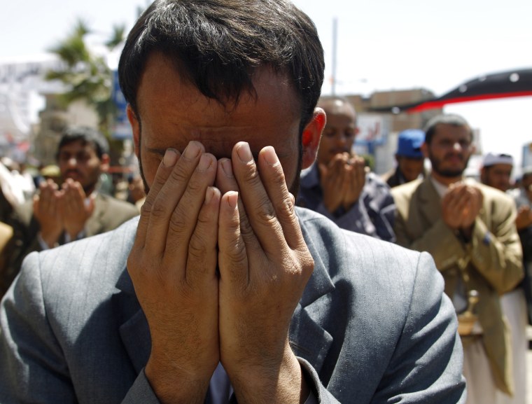 Image: Anti-government protester prays during a rally outside Sanaa University