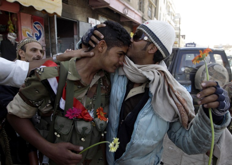 Image: A Yemeni army soldier is kissed by a demonstrator after receiving flowers while standing guard to protect anti-government protesters during a demonstration demanding the resignation of Yemeni President Ali Abdullah Saleh, in Sanaa