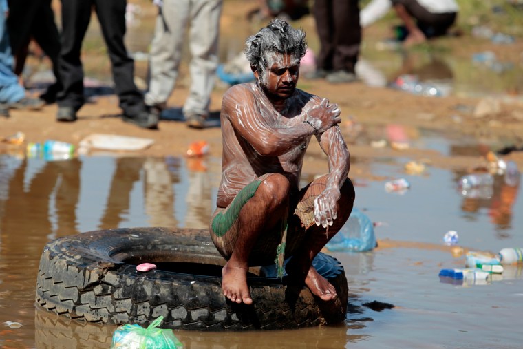 Image: A Bangladeshi migrant worker washes himself in a puddle of water at the Libyan and Tunisian border crossing of Ras Jdir after fleeing unrest in Libya