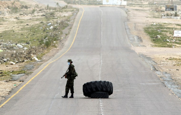 Image: A rebel holds his rifle at a checkpoint in Brega