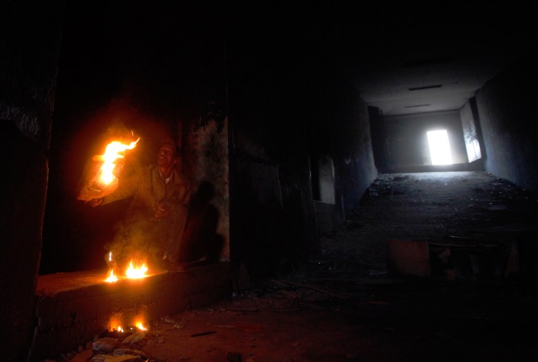 Image: A man lights a fire to look at the underground prisons that were part of the headquarters for forces loyal to Libyan leader Muammar Gaddafi in Benghazi