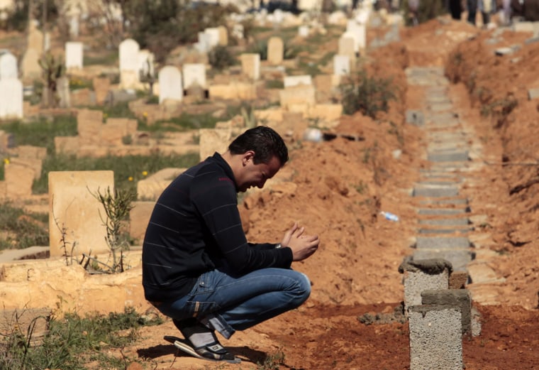 Image: A mourner reacts next to graves of rebels killed in clashes with forces loyal to Libyan leader Muammar Gaddafi in Bin Jawad, in Benghazi's Cemetery
