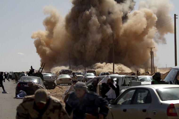 Image: Libyan rebel fighters take cover as a bo
