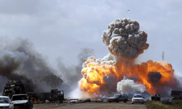 Image: Vehicles belonging to forces loyal to Libyan leader Muammar Gaddafi explode after an air strike by coalition forces, along a road between Benghazi and Ajdabiyah