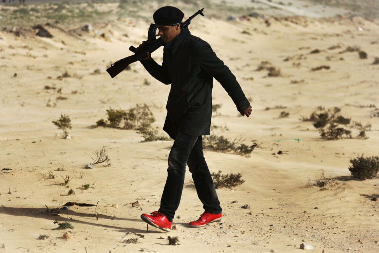 Image: A rebel fighter carries his weapon outside the northeastern Libyan town of Ajdabiyah