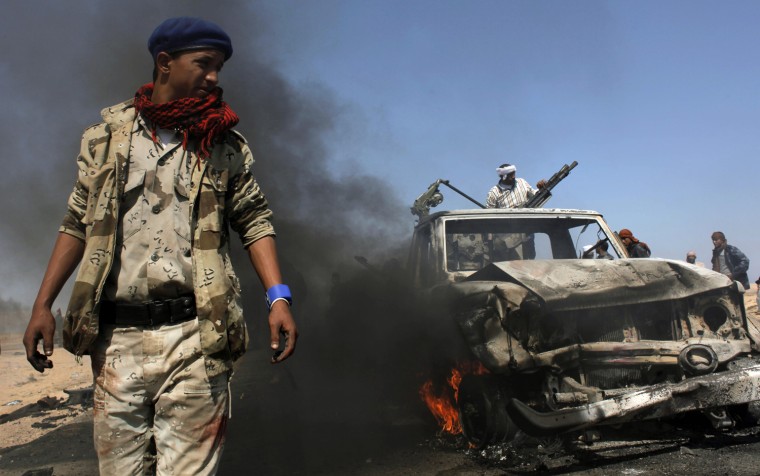 Image: Libyan rebels inspect two destroyed military vehicles of pro-Gadhafi forces that rebels claim were targeted by a NATO strike along the front line near Brega.