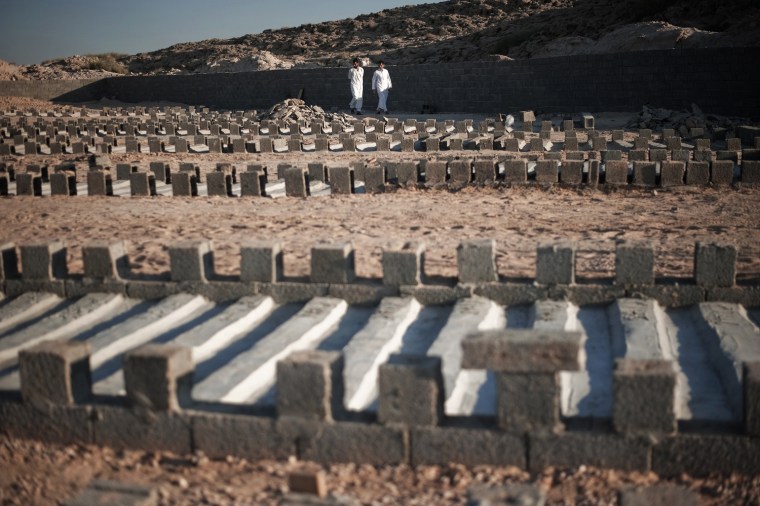 Libyans walk past the graves of Gadhafi soldiers killed since the beginning of the uprising at a cemetery for fallen loyalists in Misrata on June 24, 2011.