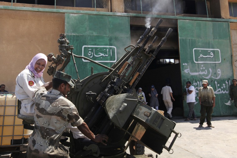 A Libyan woman reacts as she fires an anti-aircraft gun during training with a rebel army officer in Benghazi on July 11, 2011
