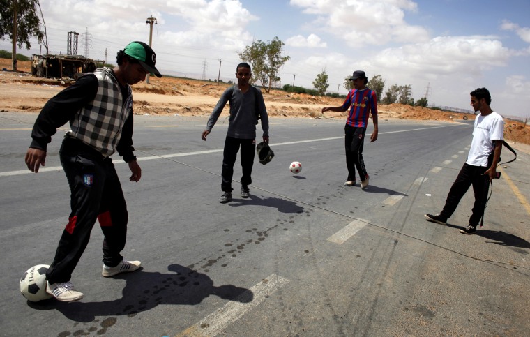 Image: Libyan rebel fighters play with soccer balls as they wait at a staging area near the village of Shal Ghouda in western Libya