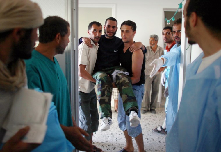 Image: A Libyan rebel fighter with a wounded leg is carried in the operating room at the Bir Muammar Hospital on the outskirts of Zawiyah