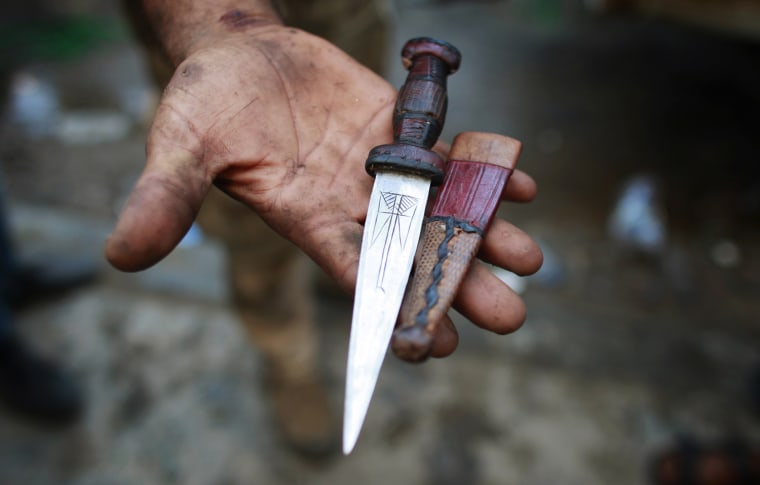 Image: A Libyan rebel fighter holds a knife seized from a man the rebels said was a captured Libyan Army soldier in Zawiyah