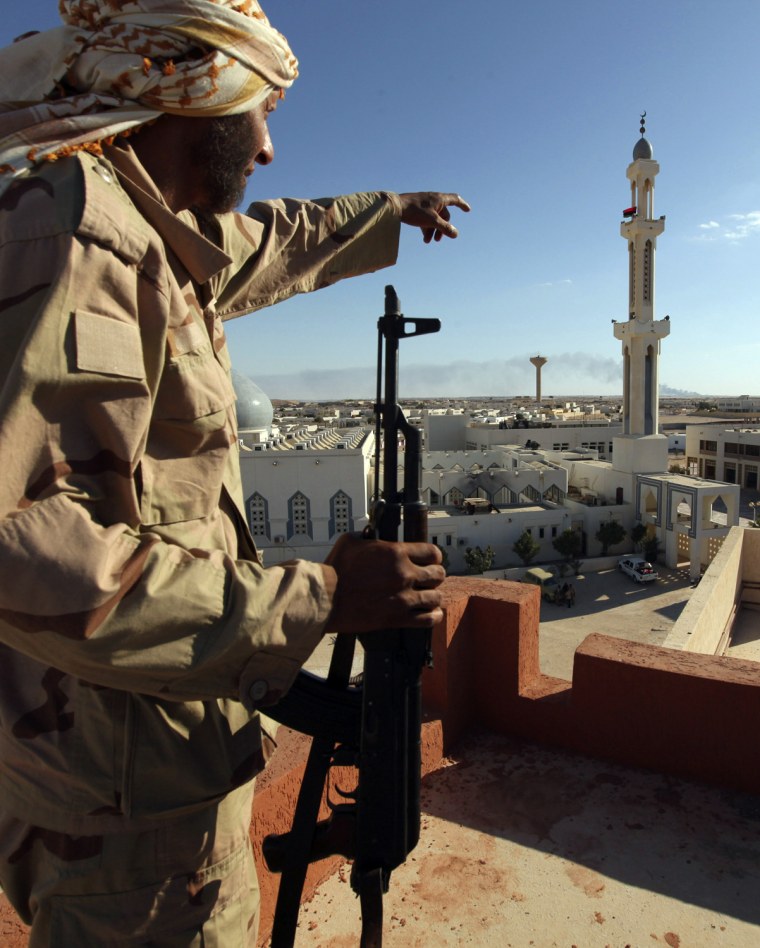 Image: A rebel fighter points towards a mosque in Brega