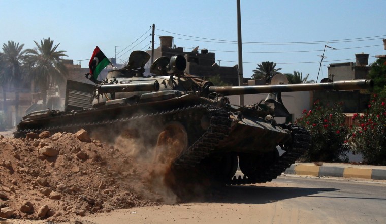 Image: A Libyan rebel tank drives over a sand barricade as rebels advance