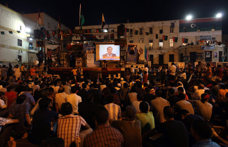 Image: People watch a speech by Libyan defector Abdul Salam Galod, a dissident of Muammar Gaddafi, near the courthouse in Benghazi
