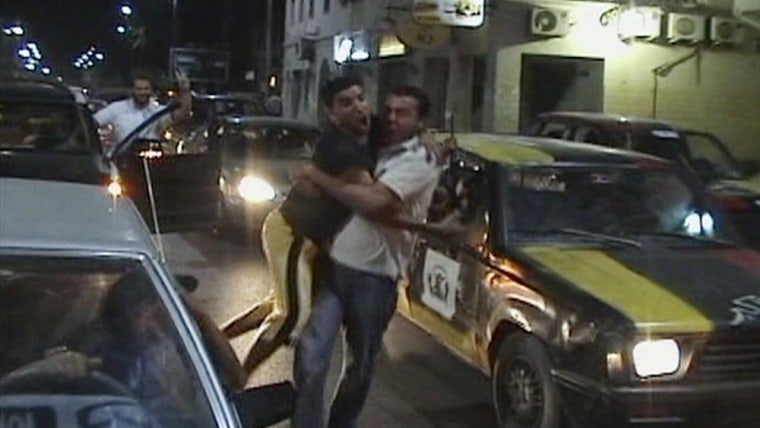 Image: Frame grab of men hugging, as they celebrate the arrival of rebel fighters in Tripoli, while they stand amid cars in Misrata