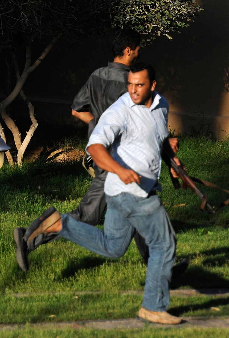 Image: Gunmen loyal to Libyan leader Muammar Gaddafi run through the grounds of the Rixos hotel in Tripoli