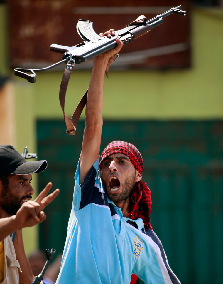 Image: A Libyan rebel fighter raises his weapon as rebels enter Tripoli's Qarqarsh district
