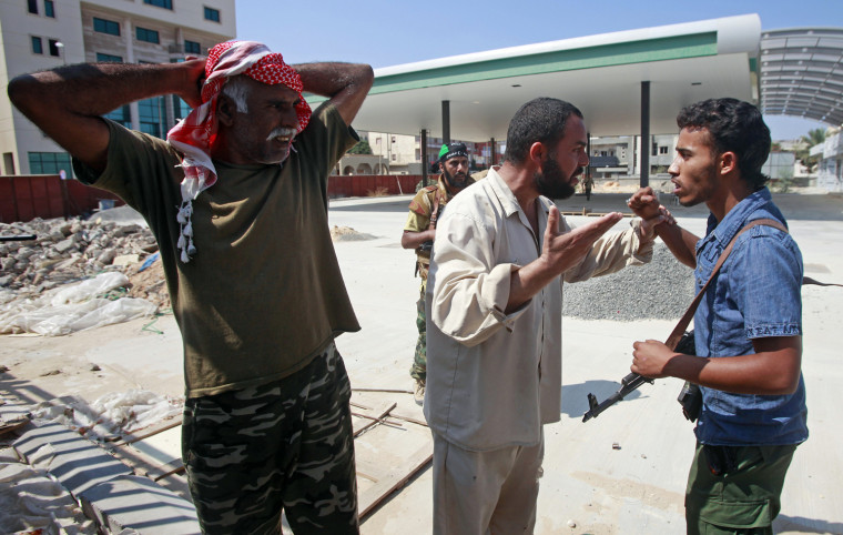 Image: A man argues with a Libyan rebel fighter after rebels tried to detain one of his workmen near a checkpoint in Tripoli's Qarqarsh district