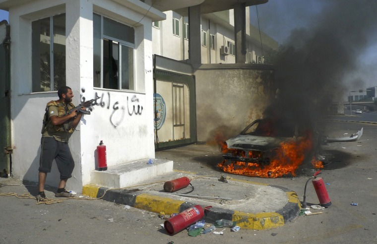 Image: A Libyan rebel fighter takes up fighting position during an attack by pro-Gaddafi forces after rebels seized a Gaddafi army women's officer training center in Tripoli