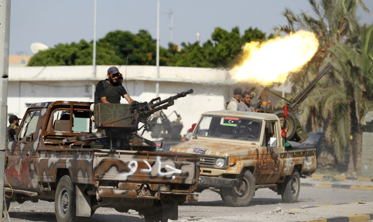 Image: A Libyan rebel fighter fires from the back of his vehicle towards Bab al Aziziya compound in Tripoli