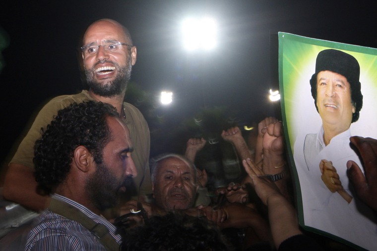 Image: Saif al-Islam Kadhafi, son of Libyan leader Moamer Kadhafi (portrait), is surrounded by supporters and journalists at his father's residential complex in the capital Tripoli