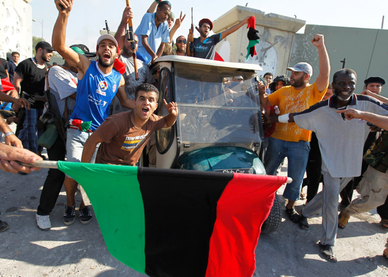 Image: Libyan rebel fighters celebrate near a golf buggy belonging to Muammar Gaddafi at the entrance of Bab al Aziziya  compound in Tripoli