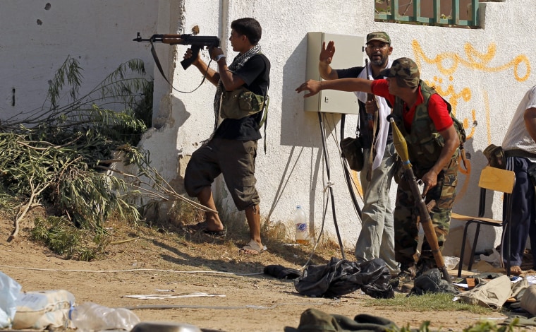 Image: A Libyan rebel fighter fires his machine gun as they make a final push to flush out pro-Gaddafi forces in Tripoli